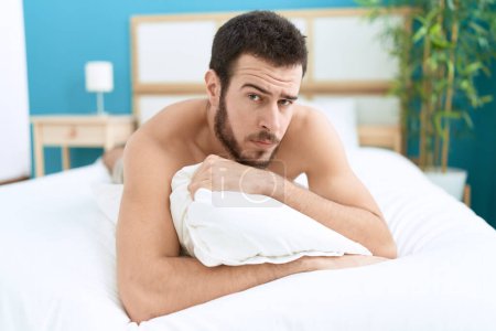 Foto de Joven hombre hispano acostado en la cama con expresión relajada en el dormitorio - Imagen libre de derechos