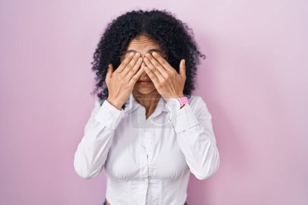 Photo for Hispanic woman with curly hair standing over pink background rubbing eyes for fatigue and headache, sleepy and tired expression. vision problem - Royalty Free Image
