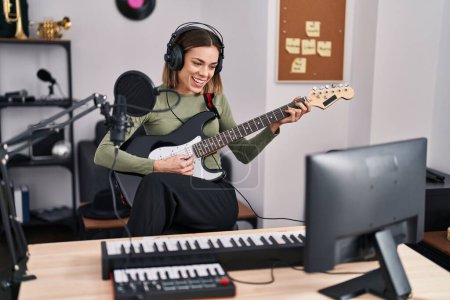 Téléchargez les photos : Young beautiful hispanic woman musician playing electrical guitar at music studio - en image libre de droit