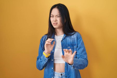 Téléchargez les photos : Jeune femme asiatique debout sur fond jaune expression dégoûtée, mécontent et craintif faire visage dégoût parce que réaction d'aversion. - en image libre de droit