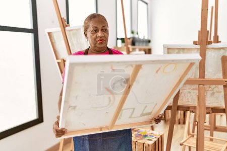 Foto de Senior afroamericana mujer buscando dibujar lienzo en estudio de arte - Imagen libre de derechos