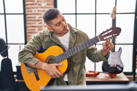 Photo for Young hispanic man musician playing classical guitar at music studio - Royalty Free Image