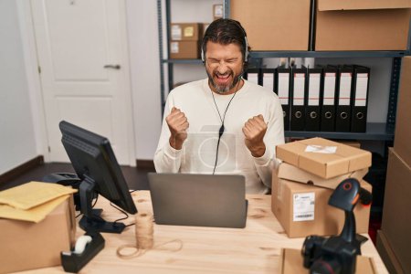Photo for Handsome middle age man working at small business ecommerce wearing headset screaming proud, celebrating victory and success very excited with raised arms - Royalty Free Image