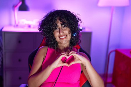 Téléchargez les photos : Young middle eastern woman streamer smiling confident doing heart symbol with hands at gaming room - en image libre de droit