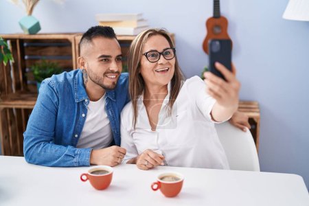 Téléchargez les photos : Man and woman mother and son drinking coffee make selfie by smartphone at home - en image libre de droit