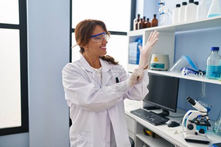 Photo for Young latin woman wearing scientist uniform and gloves at laboratory - Royalty Free Image