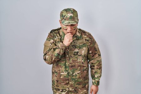 Foto de Joven hispano vestido con uniforme camuflaje del ejército sintiéndose mal y tosiendo como síntoma de frío o bronquitis. concepto de atención sanitaria. - Imagen libre de derechos