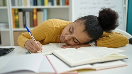 Photo for Young african american woman student taking notes tired at the library - Royalty Free Image
