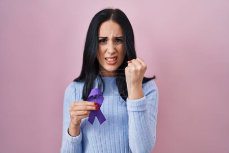 Photo for Hispanic woman holding purple ribbon awareness annoyed and frustrated shouting with anger, yelling crazy with anger and hand raised - Royalty Free Image
