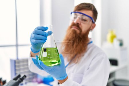 Photo for Young redhead man wearing scientist uniform holding test tube at laboratory - Royalty Free Image
