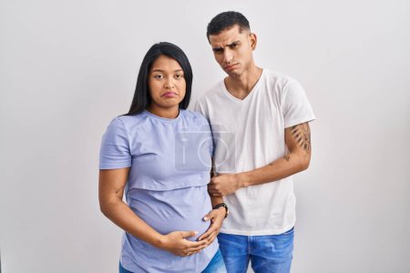Photo for Young hispanic couple expecting a baby standing over background depressed and worry for distress, crying angry and afraid. sad expression. - Royalty Free Image