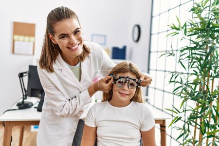 Photo for Woman and girl oculist and patient examining vision using optometrist glasses at clinic - Royalty Free Image