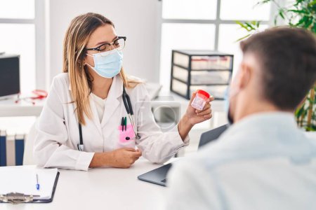 Téléchargez les photos : Jeune homme et femme médecin et patient portant un masque médical tenant un tube à essai d'urine à la clinique - en image libre de droit