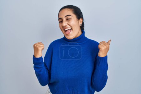 Photo for Young hispanic woman standing over isolated background very happy and excited doing winner gesture with arms raised, smiling and screaming for success. celebration concept. - Royalty Free Image