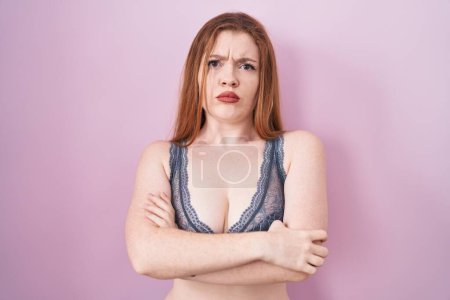 Photo for Redhead woman wearing lingerie over pink background skeptic and nervous, disapproving expression on face with crossed arms. negative person. - Royalty Free Image