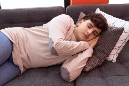 Téléchargez les photos : Homme non binaire couché sur un canapé dormant à la maison - en image libre de droit