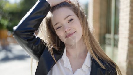 Photo for Young blonde woman smiling confident combing hair with hand at street - Royalty Free Image