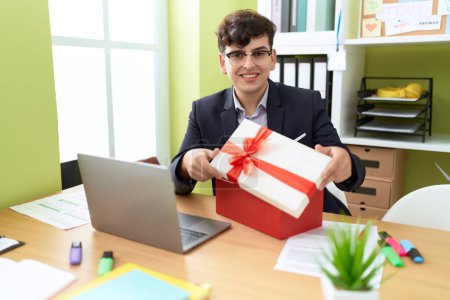 Foto de Non binary man business worker unpacking gift at office - Imagen libre de derechos