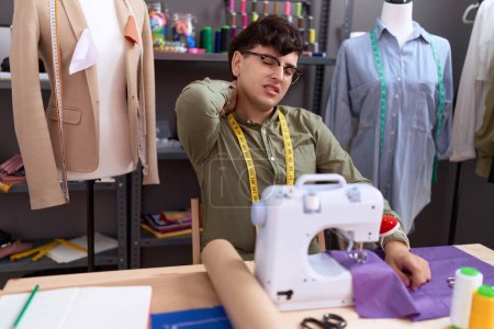 Foto de Non binary man tailor stressed using sewing machine at atelier - Imagen libre de derechos