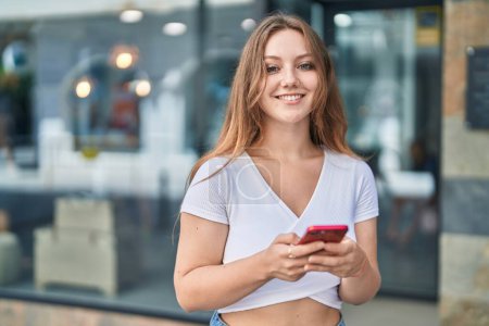Photo for Young blonde woman smiling confident using smartphone at street - Royalty Free Image