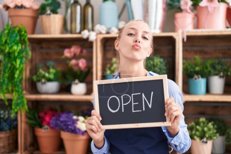 Foto de Young caucasian woman working at florist holding open sign looking at the camera blowing a kiss being lovely and sexy. love expression. - Imagen libre de derechos