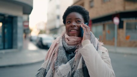 Téléchargez les photos : Jeune femme afro-américaine souriante confiante parler sur le smartphone à la rue - en image libre de droit