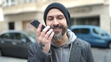 Téléchargez les photos : Jeune chauve envoyant un message vocal avec smartphone dans la rue - en image libre de droit