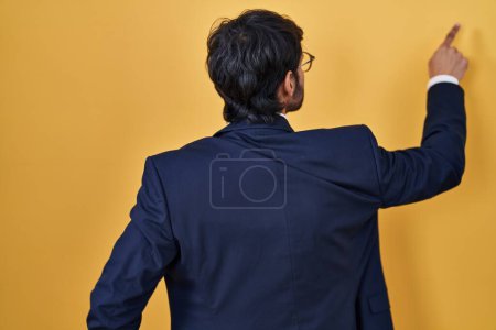 Téléchargez les photos : Handsome latin man standing over yellow background posing backwards pointing ahead with finger hand - en image libre de droit