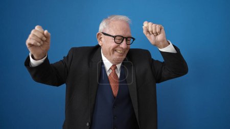 Téléchargez les photos : Senior souriant et dansant sur fond bleu isolé - en image libre de droit