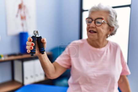 Photo for Senior grey-haired woman physitherapist patient having rehab session using hand grip at physitherapy clinic - Royalty Free Image