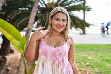 Téléchargez les photos : Jeune femme hispanique à l'extérieur par le parc souriant heureux pointant avec la main et le doigt - en image libre de droit
