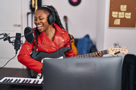 Photo for African american woman musician singing song playing guitar at music studio - Royalty Free Image