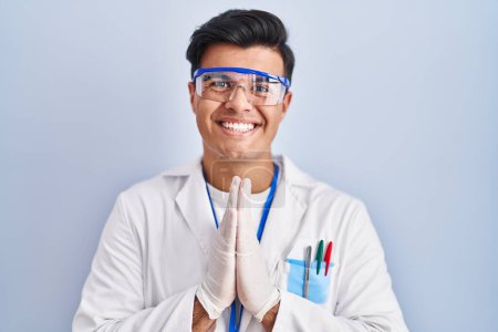 Photo for Hispanic man working as scientist praying with hands together asking for forgiveness smiling confident. - Royalty Free Image