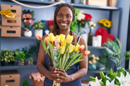 Foto de Mujer afroamericana florista sosteniendo ramo de flores en la tienda de flores - Imagen libre de derechos