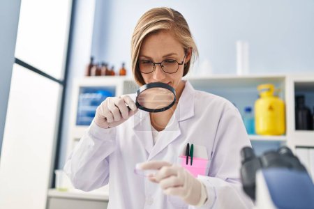 Téléchargez les photos : Young blonde woman scientist looking sample using loupe at laboratory - en image libre de droit
