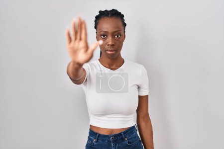 Téléchargez les photos : Beautiful black woman standing over isolated background doing stop sing with palm of the hand. warning expression with negative and serious gesture on the face. - en image libre de droit