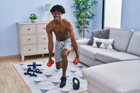 Photo for African american man training legs exercise using dumbbells at home - Royalty Free Image