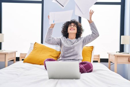 Photo for Young middle east woman using laptop throwing paperwork at bedroom - Royalty Free Image