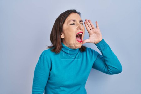 Photo for Middle age hispanic woman standing over isolated background shouting and screaming loud to side with hand on mouth. communication concept. - Royalty Free Image
