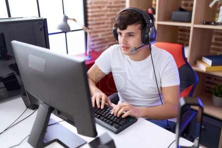 Téléchargez les photos : Non binary man streamer playing video game using computer at gaming room - en image libre de droit