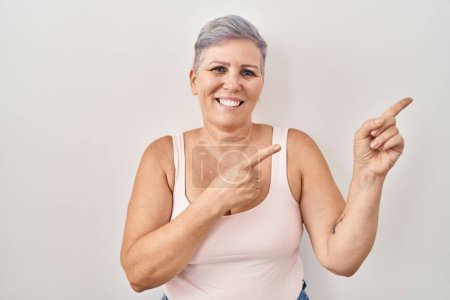 Photo for Middle age caucasian woman standing over white background smiling and looking at the camera pointing with two hands and fingers to the side. - Royalty Free Image