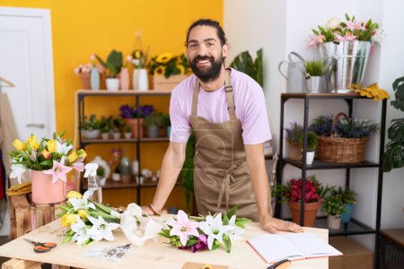 Téléchargez les photos : Jeune homme hispanique fleuriste souriant confiant debout à la boutique de fleurs - en image libre de droit