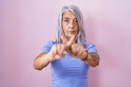 Photo for Middle age woman with tattoos standing over pink background rejection expression crossing fingers doing negative sign - Royalty Free Image