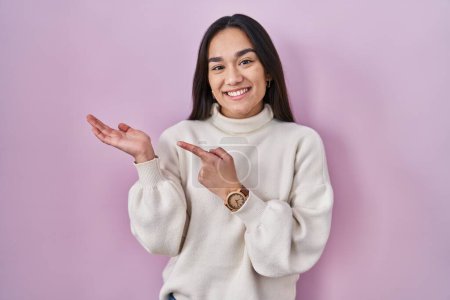 Foto de Joven mujer del sur asiático de pie sobre fondo rosa sorprendido y sonriendo a la cámara mientras se presenta con la mano y señalando con el dedo. - Imagen libre de derechos