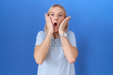 Foto de Mujer caucásica joven con camiseta azul casual asustado y sorprendido, sorpresa y expresión asombrada con las manos en la cara - Imagen libre de derechos