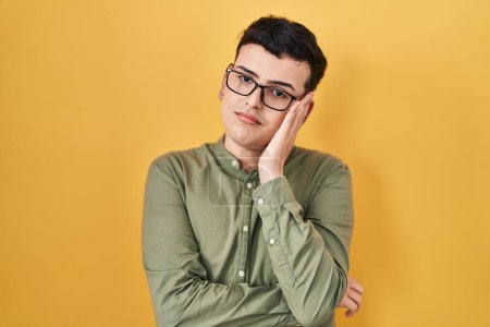 Foto de Non binary person standing over yellow background thinking looking tired and bored with depression problems with crossed arms. - Imagen libre de derechos