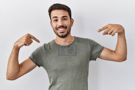 Photo for Young hispanic man with beard wearing casual t shirt over white background looking confident with smile on face, pointing oneself with fingers proud and happy. - Royalty Free Image
