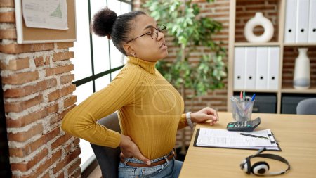 Téléchargez les photos : Jeune femme afro-américaine d'affaires souffrant de maux de dos au bureau - en image libre de droit