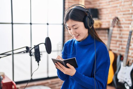 Photo for Chinese woman artist smiling confident composing song at music studio - Royalty Free Image
