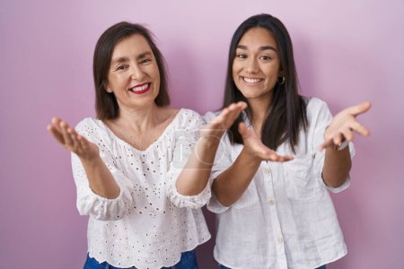Téléchargez les photos : Mère hispanique et fille ensemble souriant joyeuse offrant mains donnant assistance et acceptation. - en image libre de droit